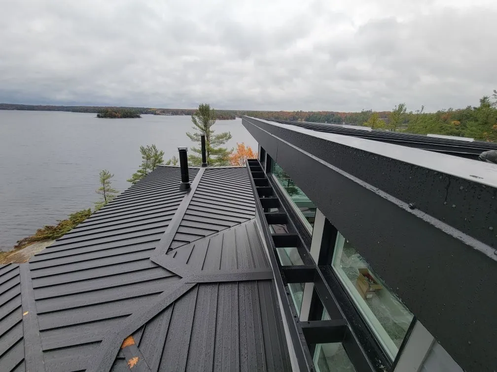 Close view along a dark eavestrough above a lakeside metal roof