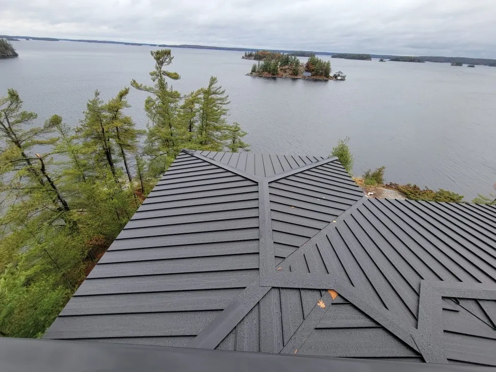Intersecting standing-seam roof planes and clean ridge lines overlooking a lake